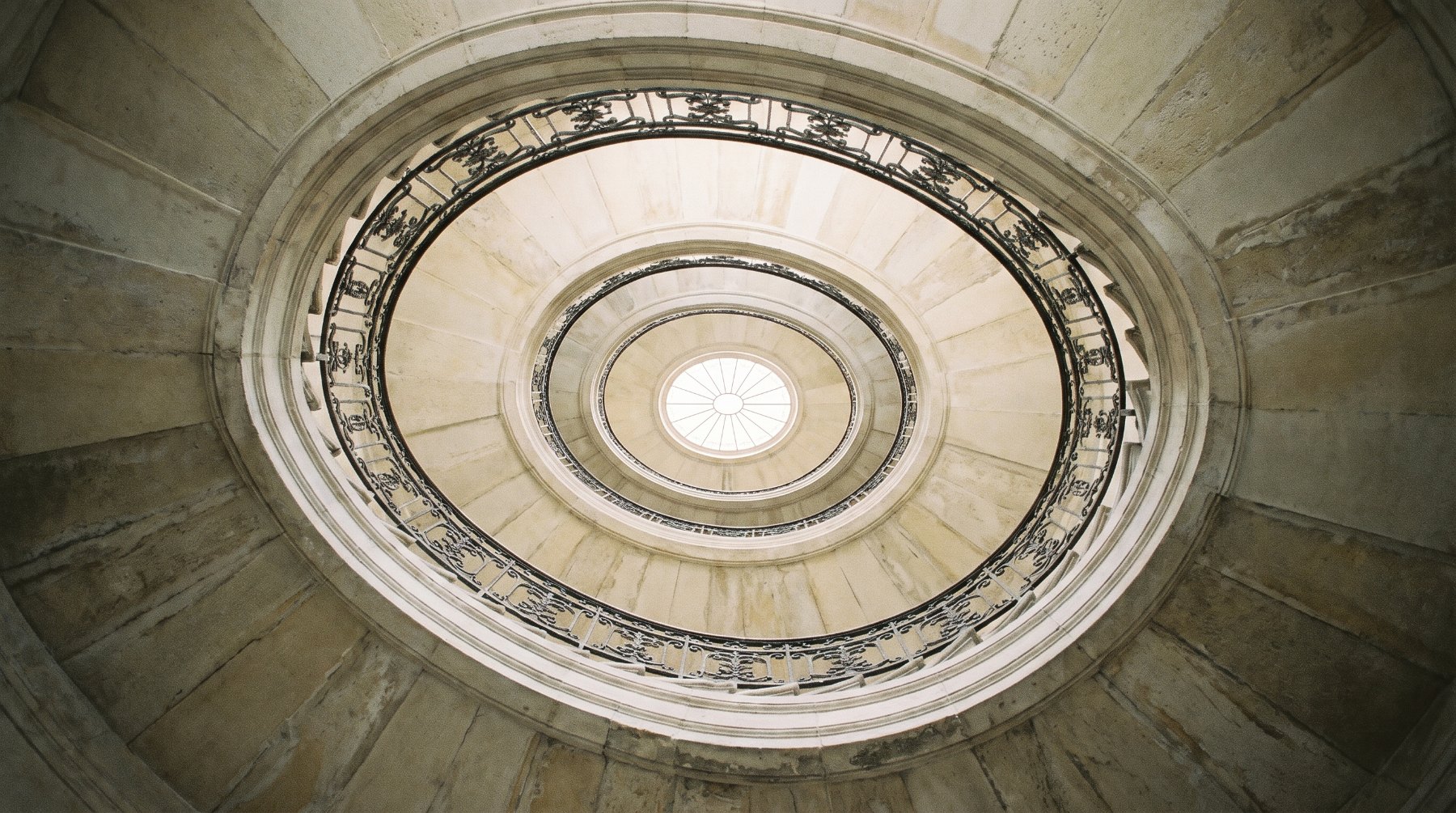 Stone spiral stairwell rising toward a skylight